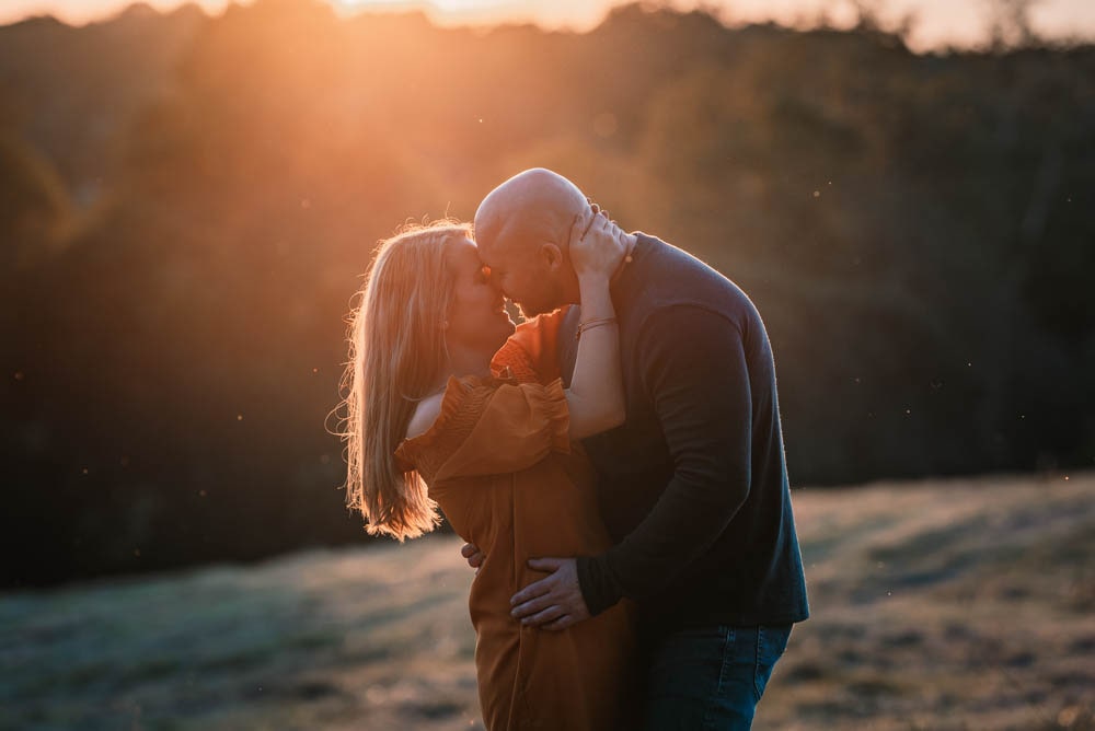 an engaged couple almost kisses in golden light