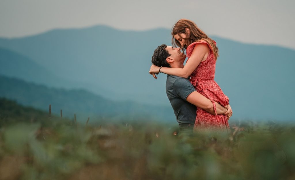 a couple embracing as the man picks up his fiance during their engagement photos