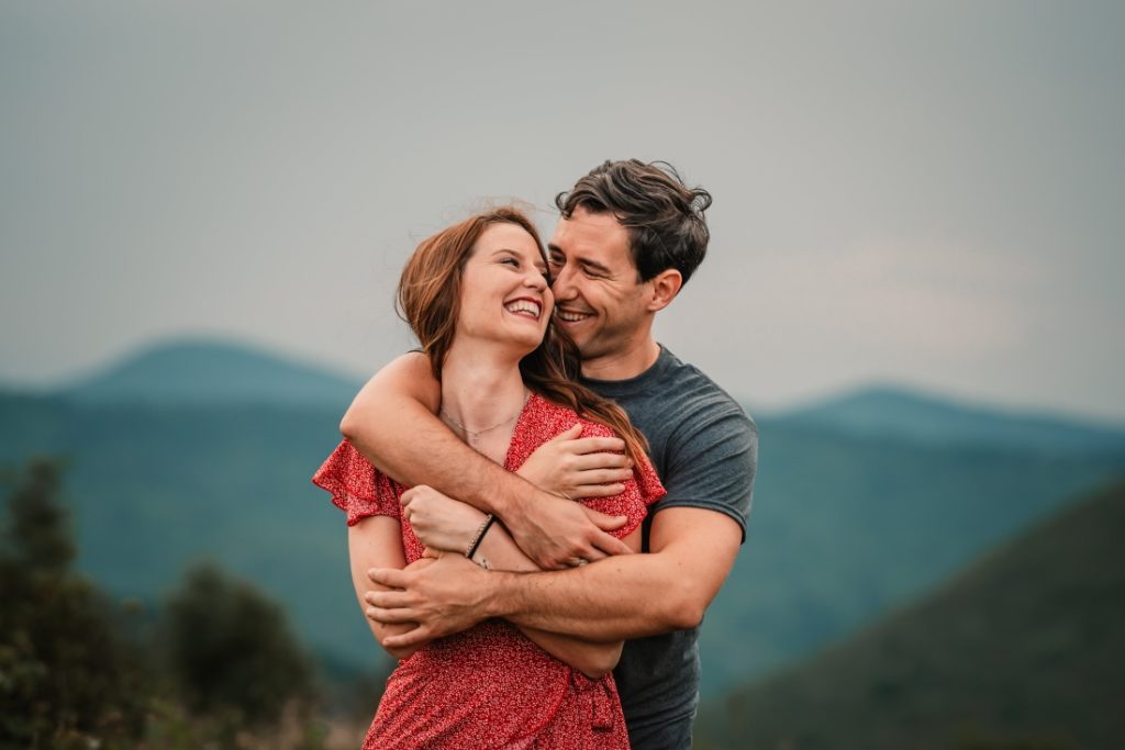 a man hugs a woman from behind and she laughs on black balsam knob