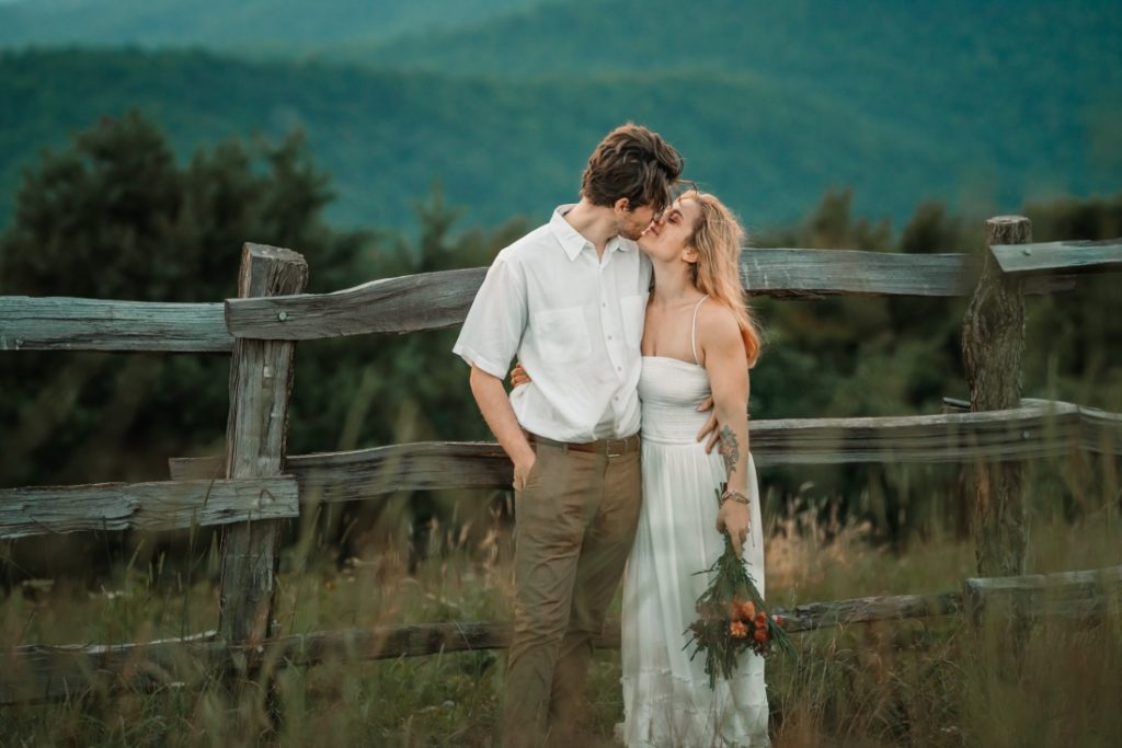 max patch elopement by a fence two people cuddle up for a kiss