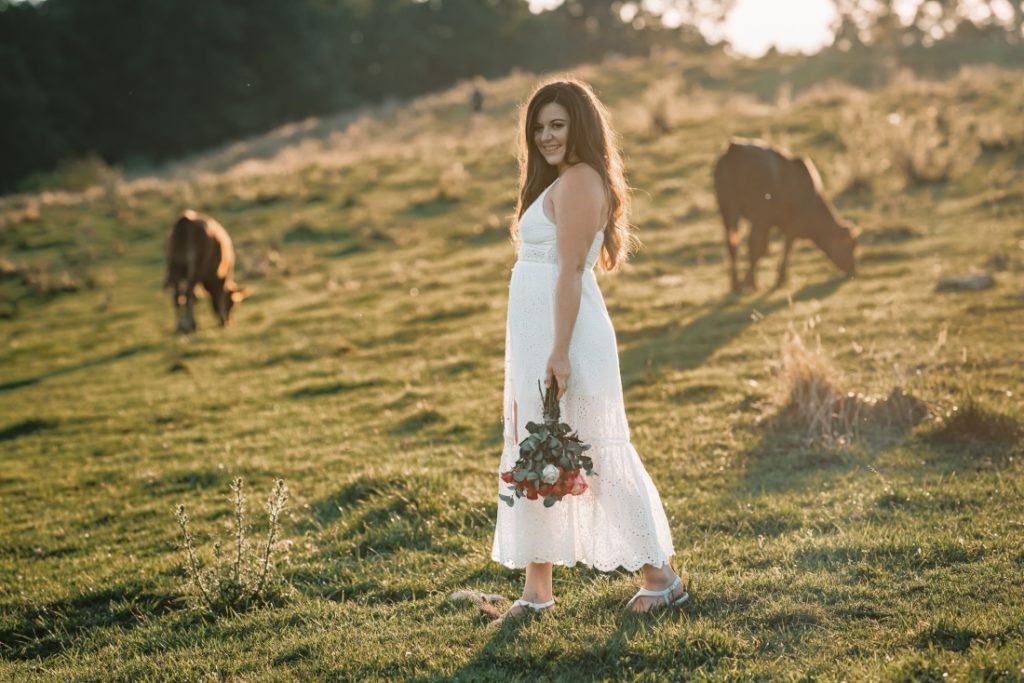 a bride holding a bouquet with cows in the background during her bearwallow mountain elopement