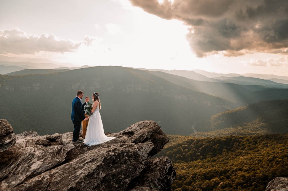 a couple saying their vows on a mountain ledge at sunset